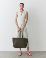 Woman wearing a dress and holding a tote bag.