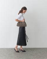 A person with a shoulder bag and wearing a long skirt and heels.