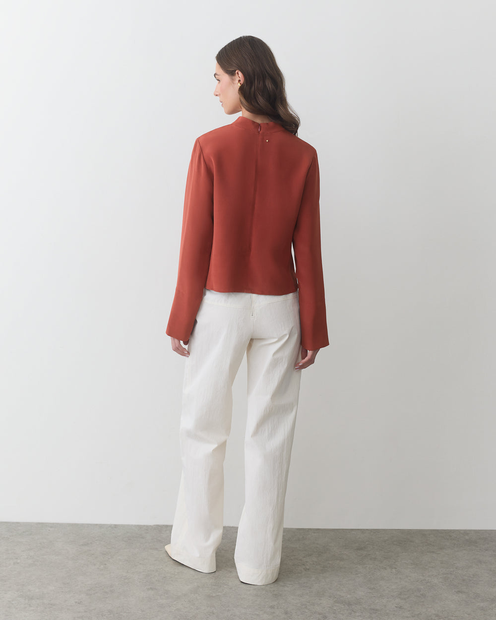 Person facing away wearing a long-sleeve top and wide-leg pants.