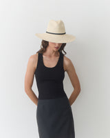 Person wearing a sleeveless top and skirt with a brimmed hat.