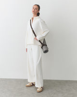 Person in relaxed outfit holding a yoga mat bag over shoulder.