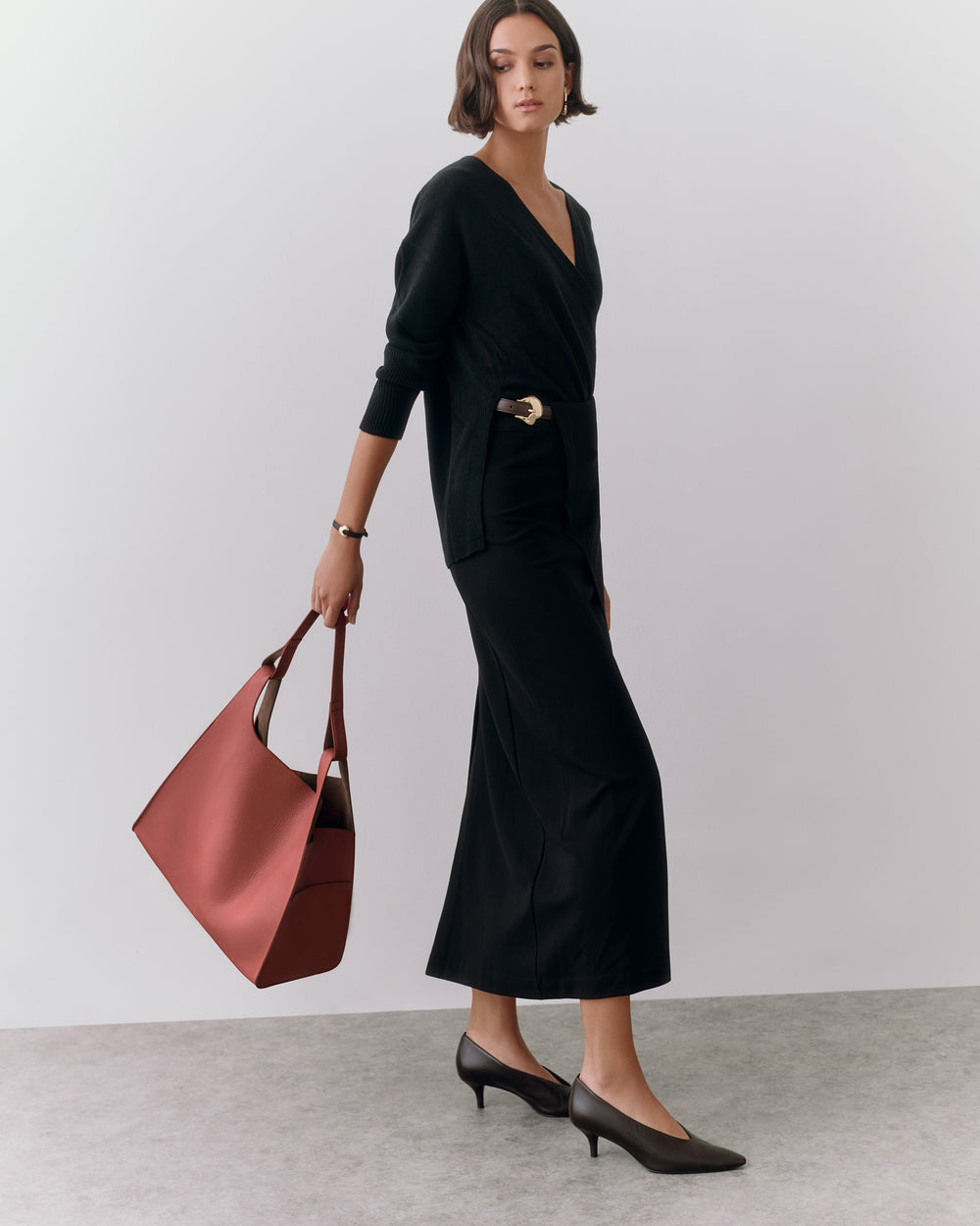 Person in a dress holding a large handbag and wearing heels.