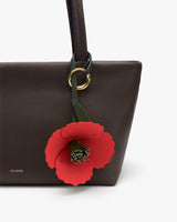 Tote bag with a flower charm on its handle.