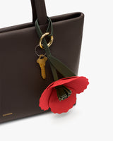 Handbag with a flower keychain and keys attached.