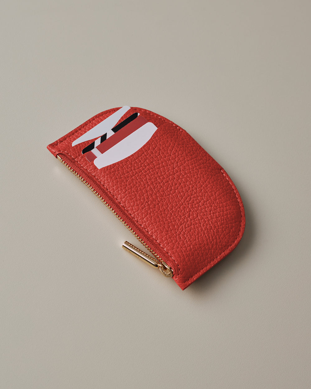 Small half-moon wallet with zipper and abstract design on the surface.