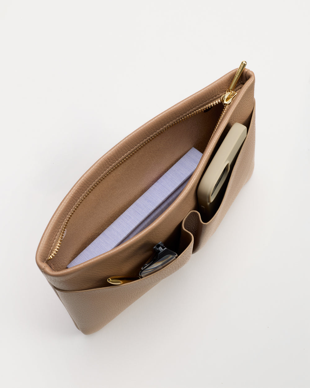 Top view of an open handbag with book, phone, and sunglasses inside.