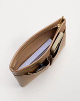 Top view of an open handbag with book, phone, and sunglasses inside.