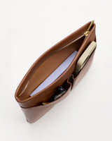 Top view of an open leather zip pouch with items inside.