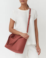 Person with shoulder bag wearing a short-sleeved top.