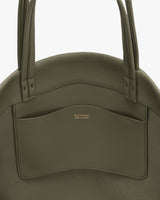 Round handbag with two handles and a front pocket.