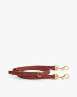 Leather strap with gold-tone clasps and a circular buckle lying flat.