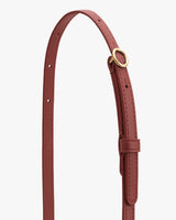 Thin leather strap with metal ring and multiple holes for adjustment.