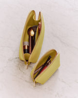 Two open makeup bags with cosmetics on a marble surface.