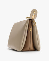 Side view of a structured handbag with gold hardware and snap closure.