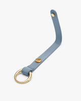 Leather strap with metal ring and button closure.