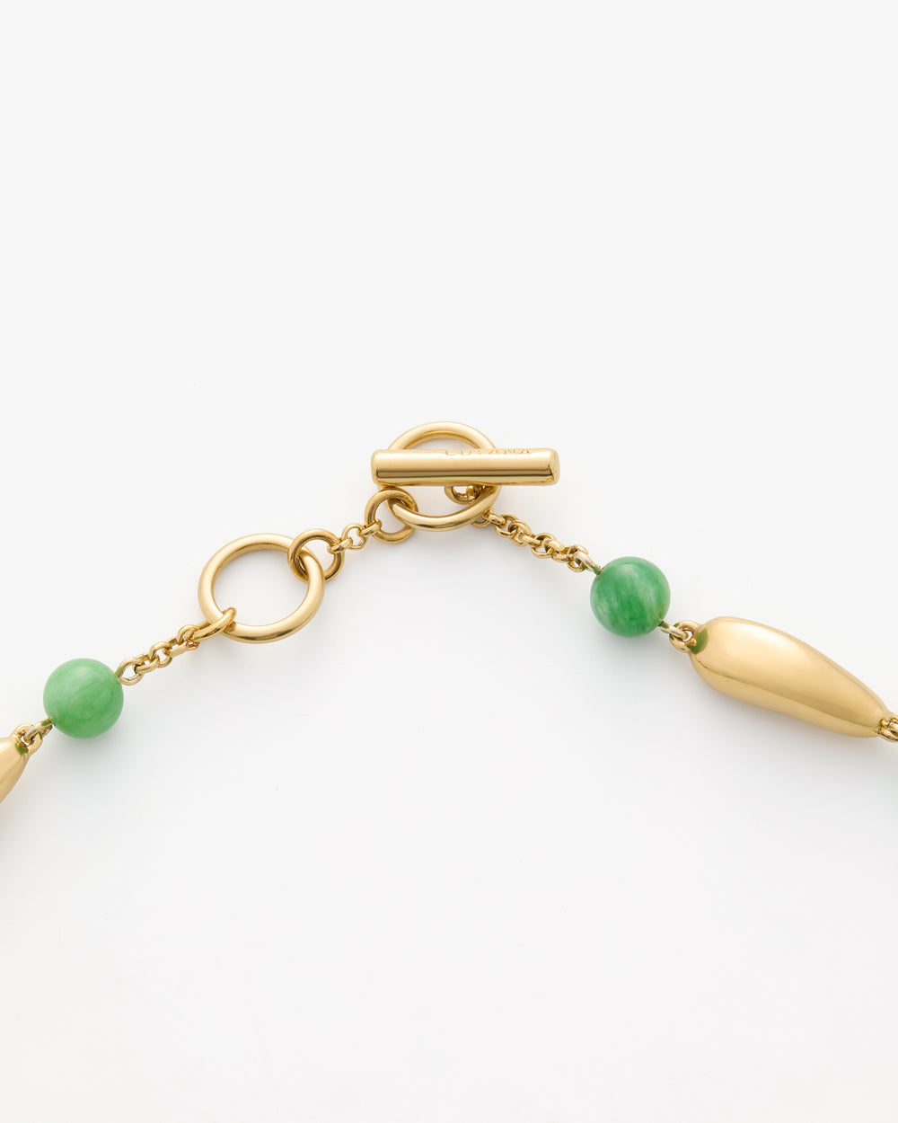 A gold toggle clasp with green beads on a chain.