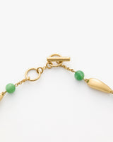 A gold toggle clasp with green beads on a chain.