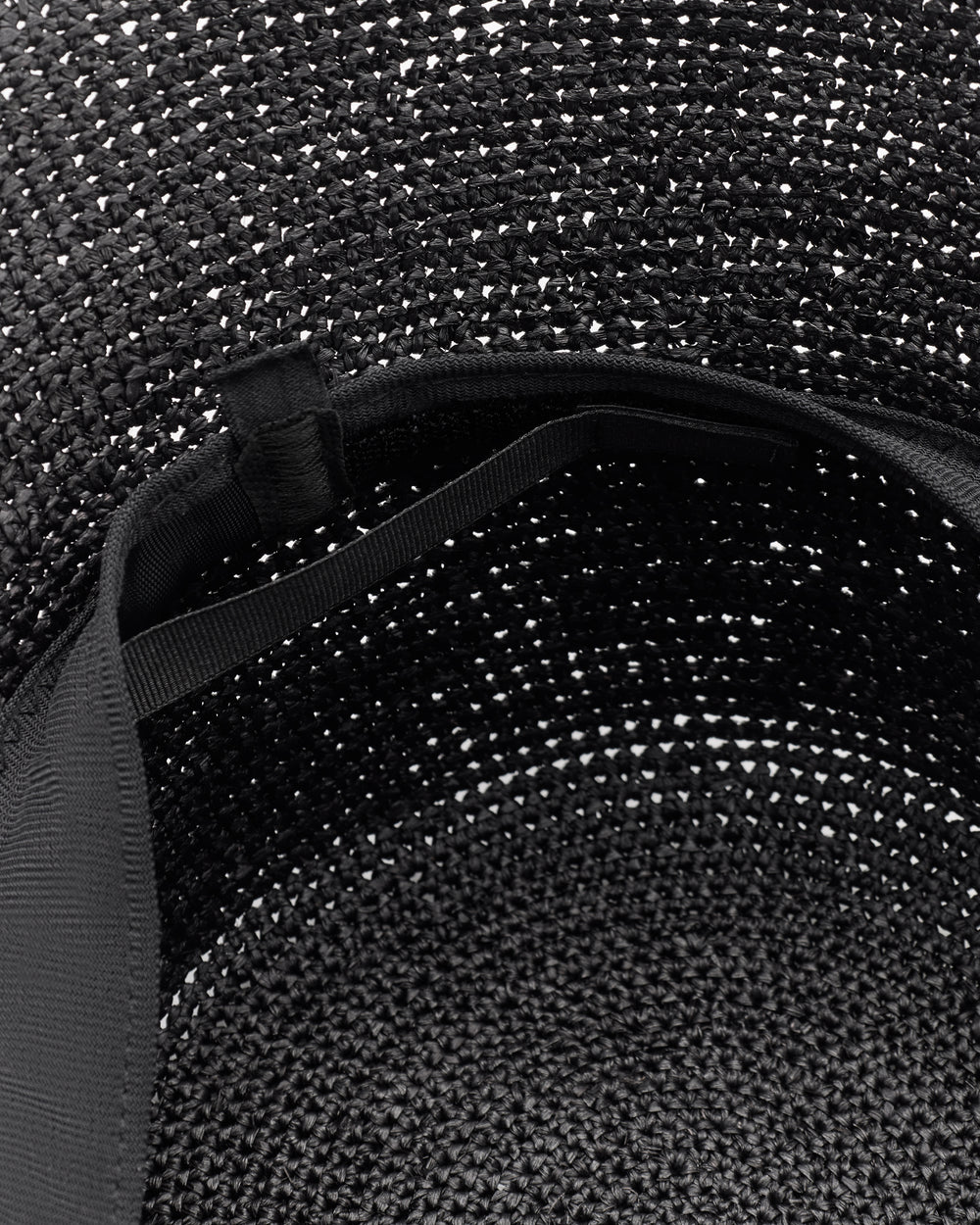 Close-up of an open woven bag with a visible strap inside.