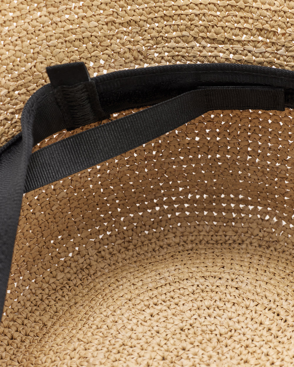 Inside view of woven hat with black strap.