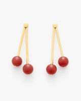 Earrings with long gold bars and round red beads at the ends.