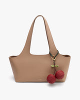 Handbag with a cherry keychain attached to the handle.
