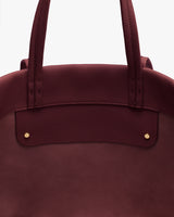Close-up of a handbag with two handles and gold rivets.