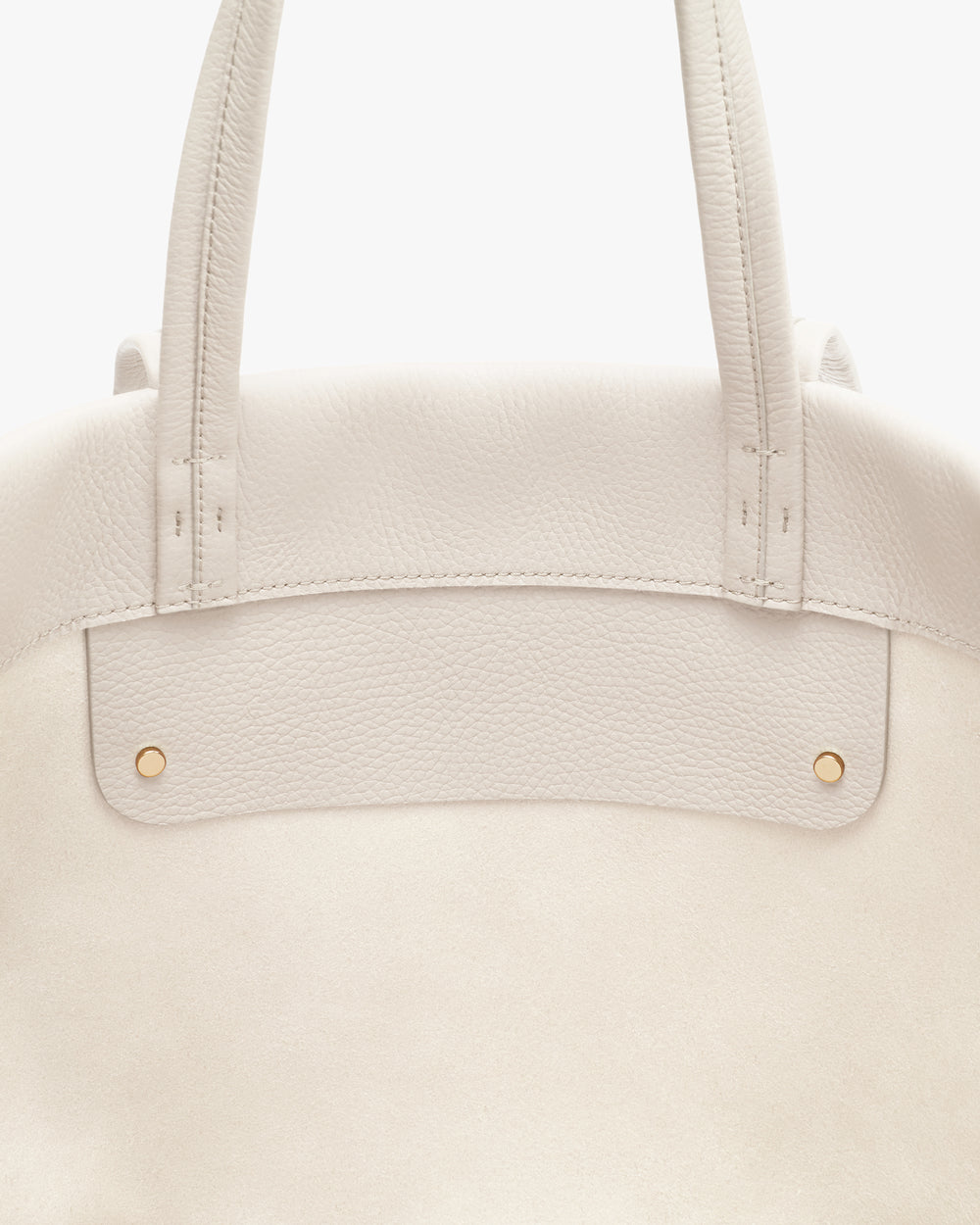 Close-up of a tote bag with two handles and gold rivet details.