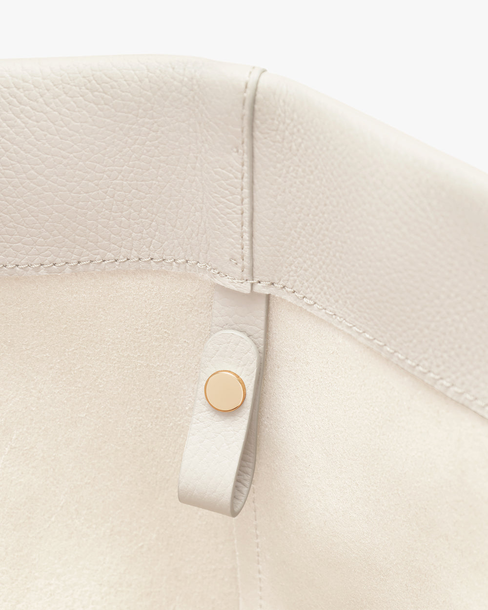 Close-up of a bag corner with a small strap and button.