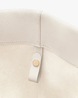Close-up of a bag corner with a small strap and button.