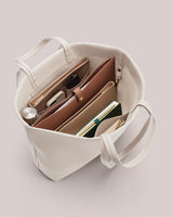 Open tote bag with various items inside including pouches and a notebook.