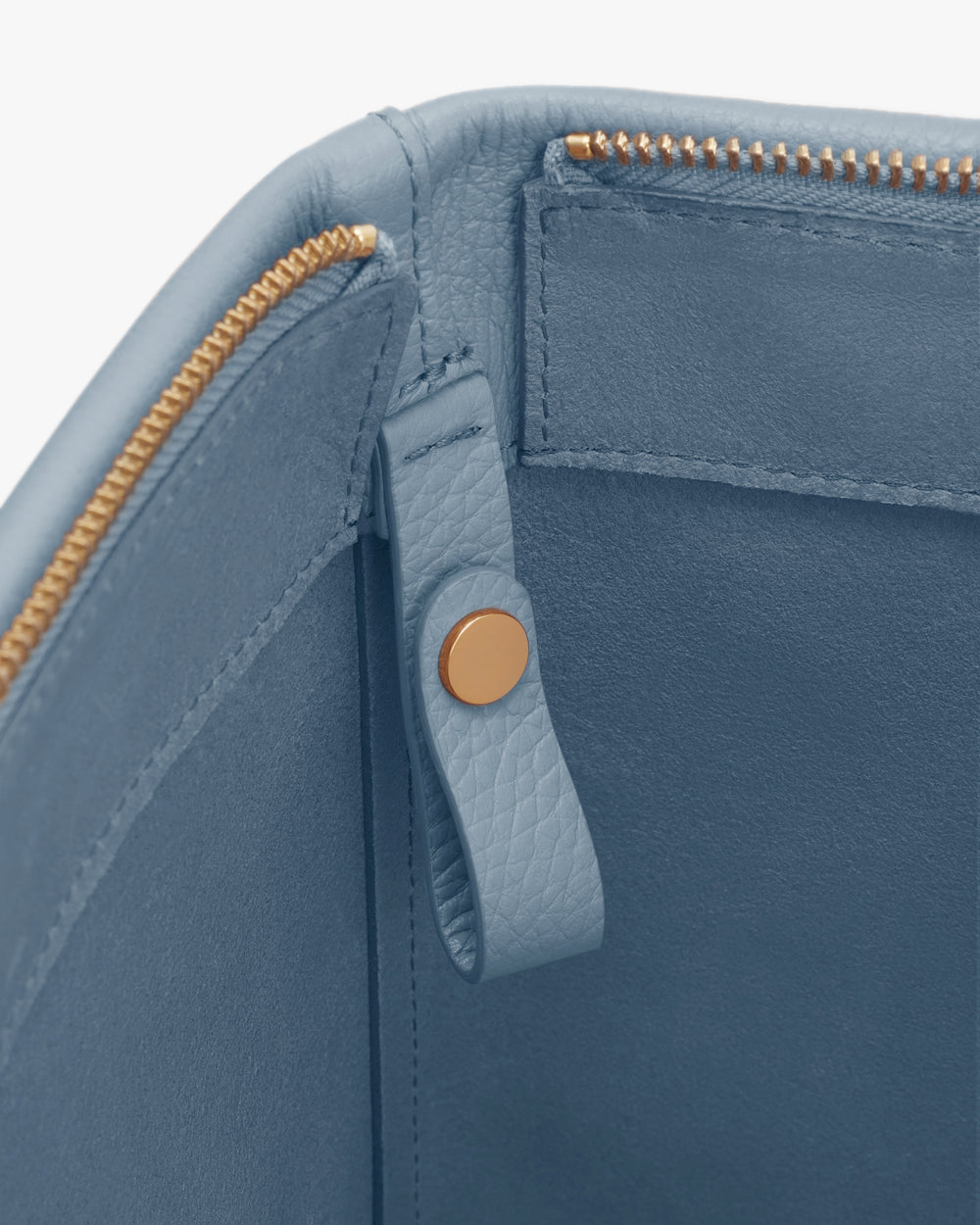 Open leather bag with zipper and button detail visible inside.