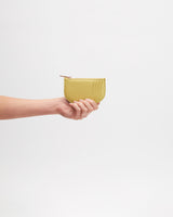 Hand holding a small zippered pouch against plain background.