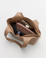 Open handbag with phone, AirPods, wallet, pouch, and cardholder inside.