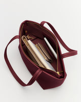 Open handbag showing a notebook, phone, and wallet inside.