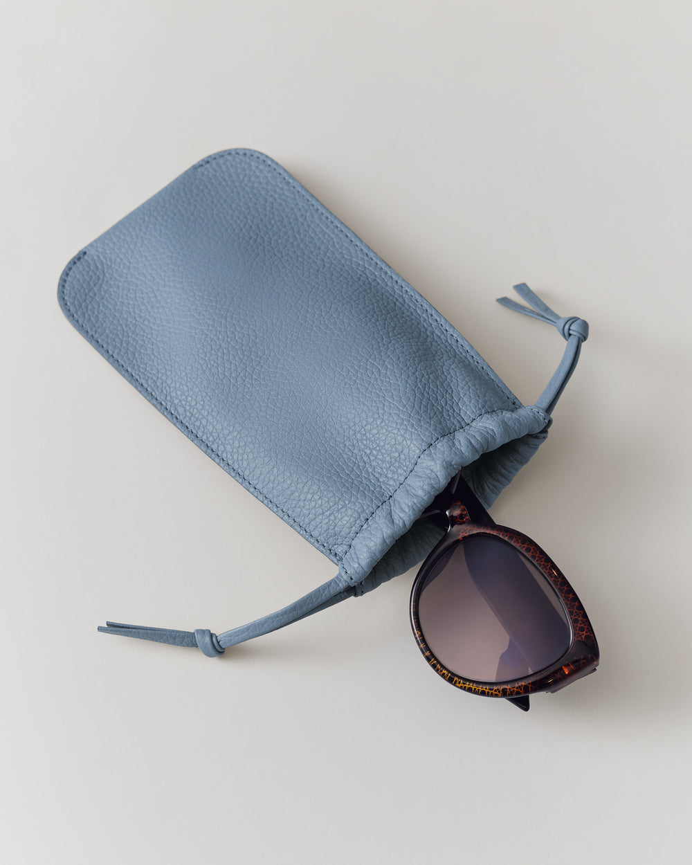Pouch with drawstrings and sunglasses partially inside.