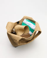 Woven tote with towel, hat, and bottle inside.