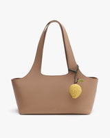 Handbag with a lemon-shaped charm hanging from the handle.