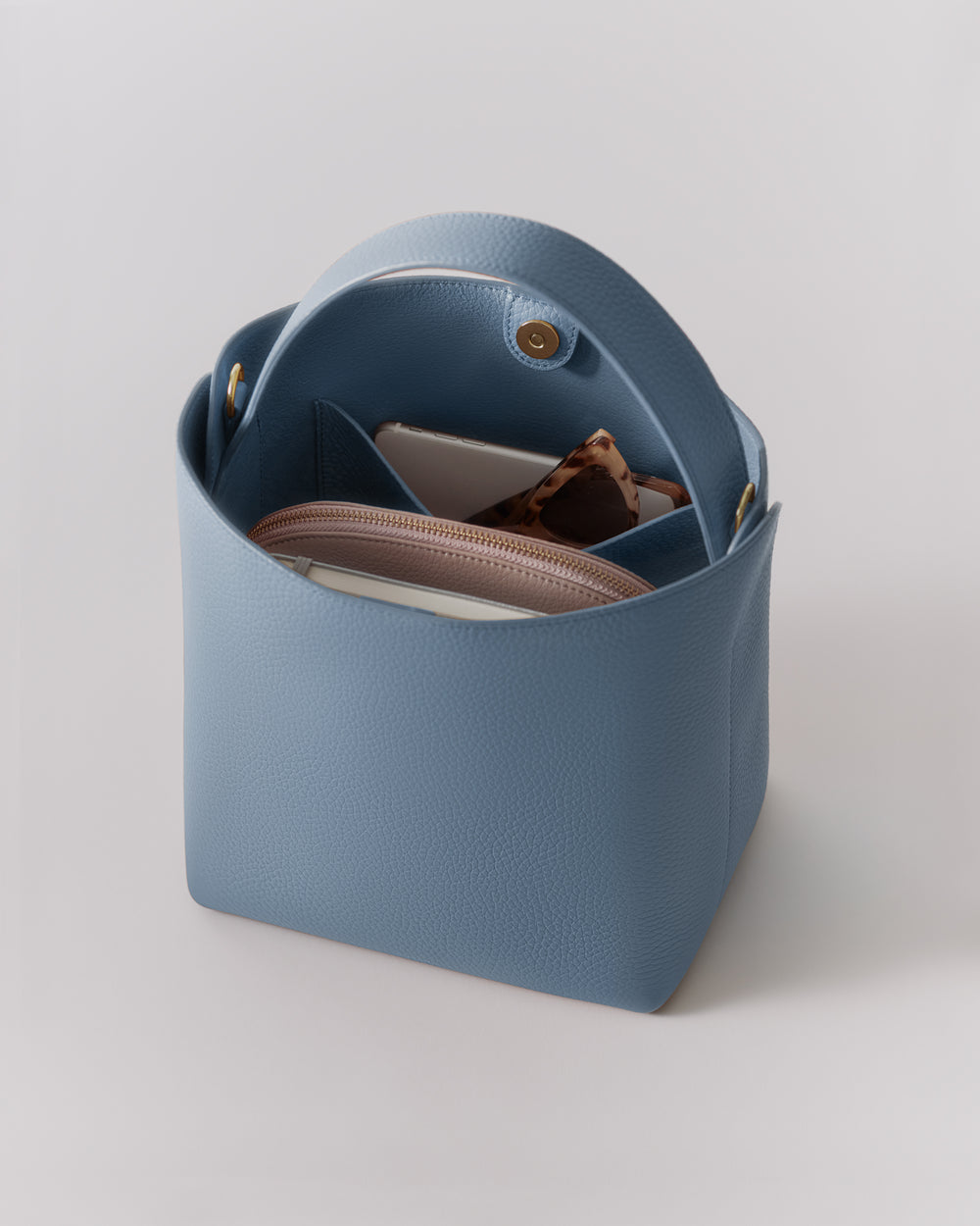 Open handbag with sunglasses and pouches inside.