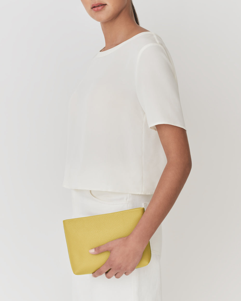 Person holding a rectangular clutch under one arm.