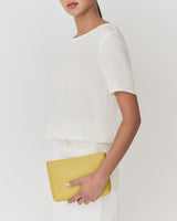 Person holding a rectangular clutch under one arm.