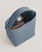 Open handbag with a zipper pouch and a snap closure strap.