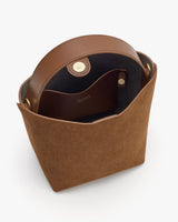 Open bucket bag with round handle and magnetic clasp.