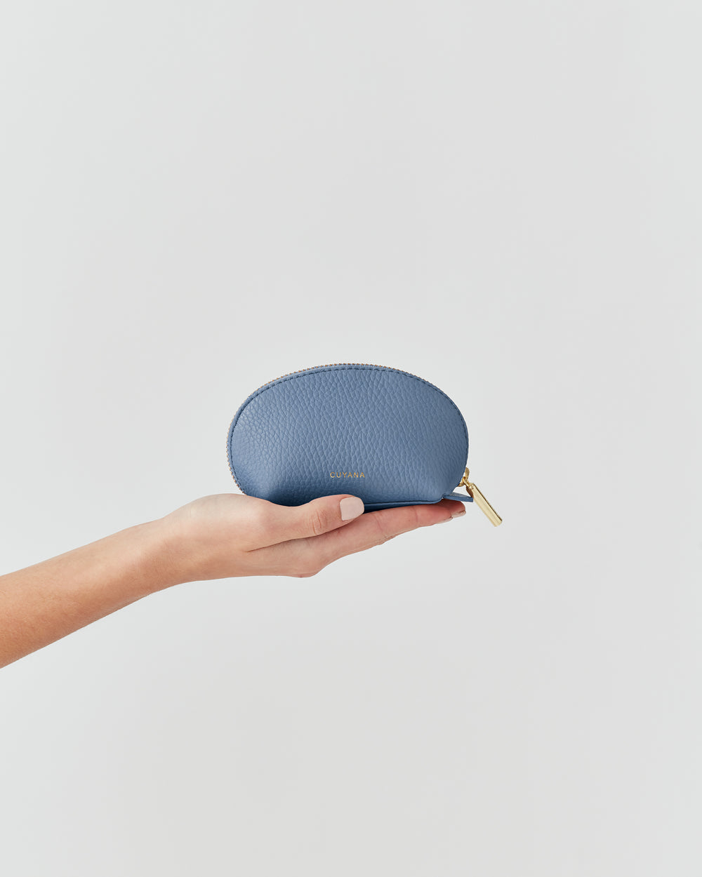 Hand holding a small zippered pouch against a plain background.