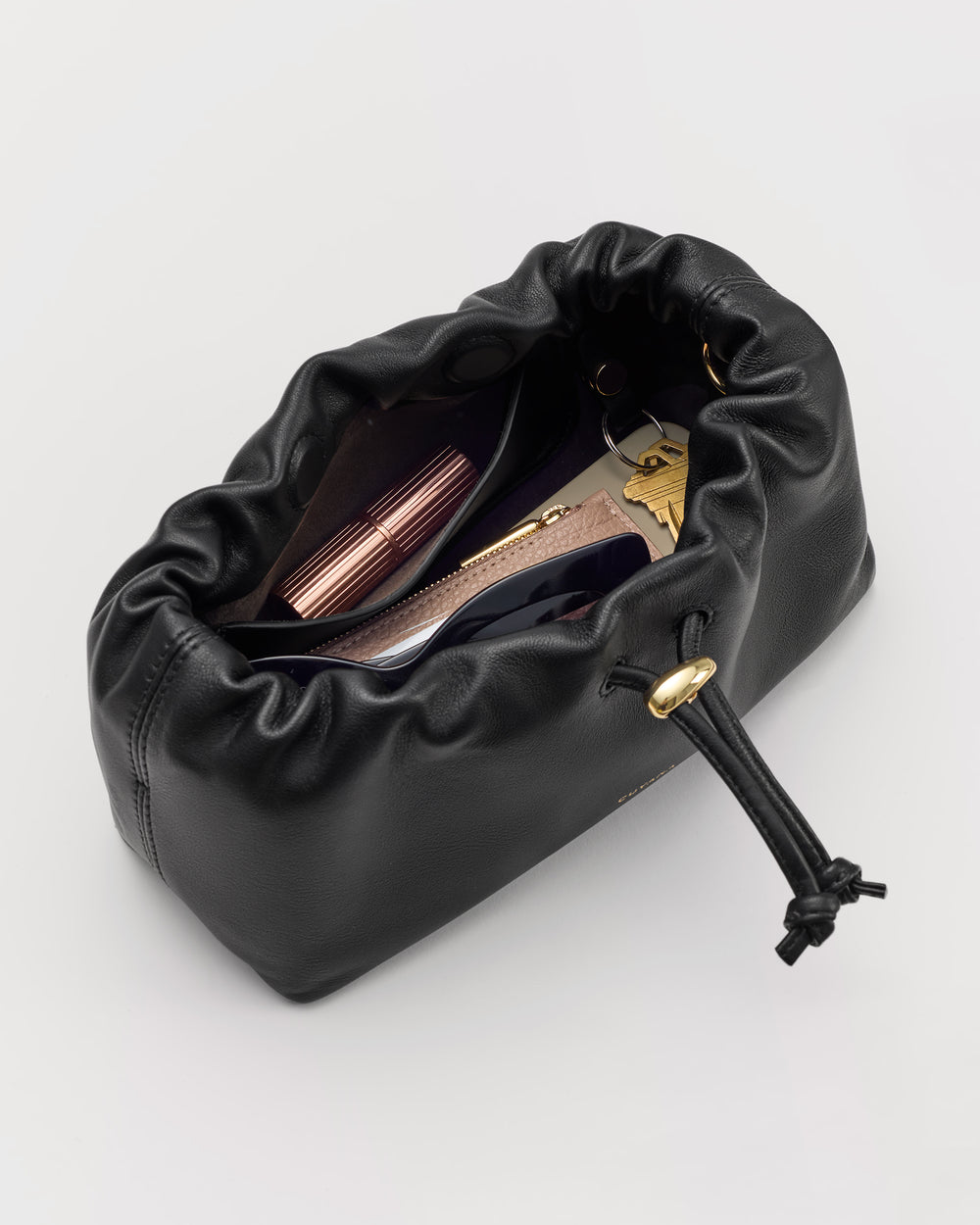 Drawstring pouch with cosmetics and card holder inside.