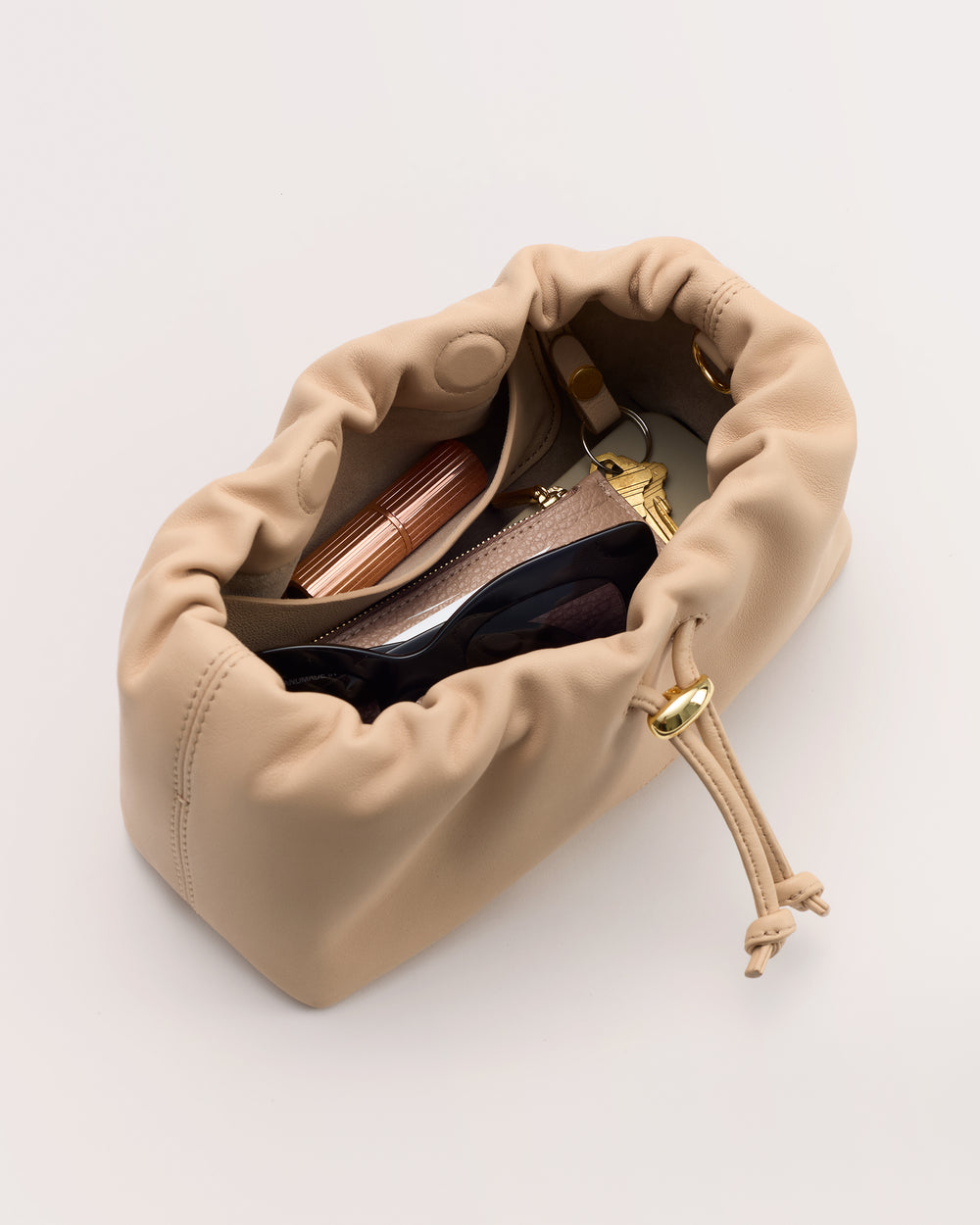 Drawstring handag containing sunglasses, lipstick, and various small items