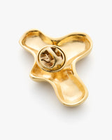 Abstract gold pin with a round fastening in the center.