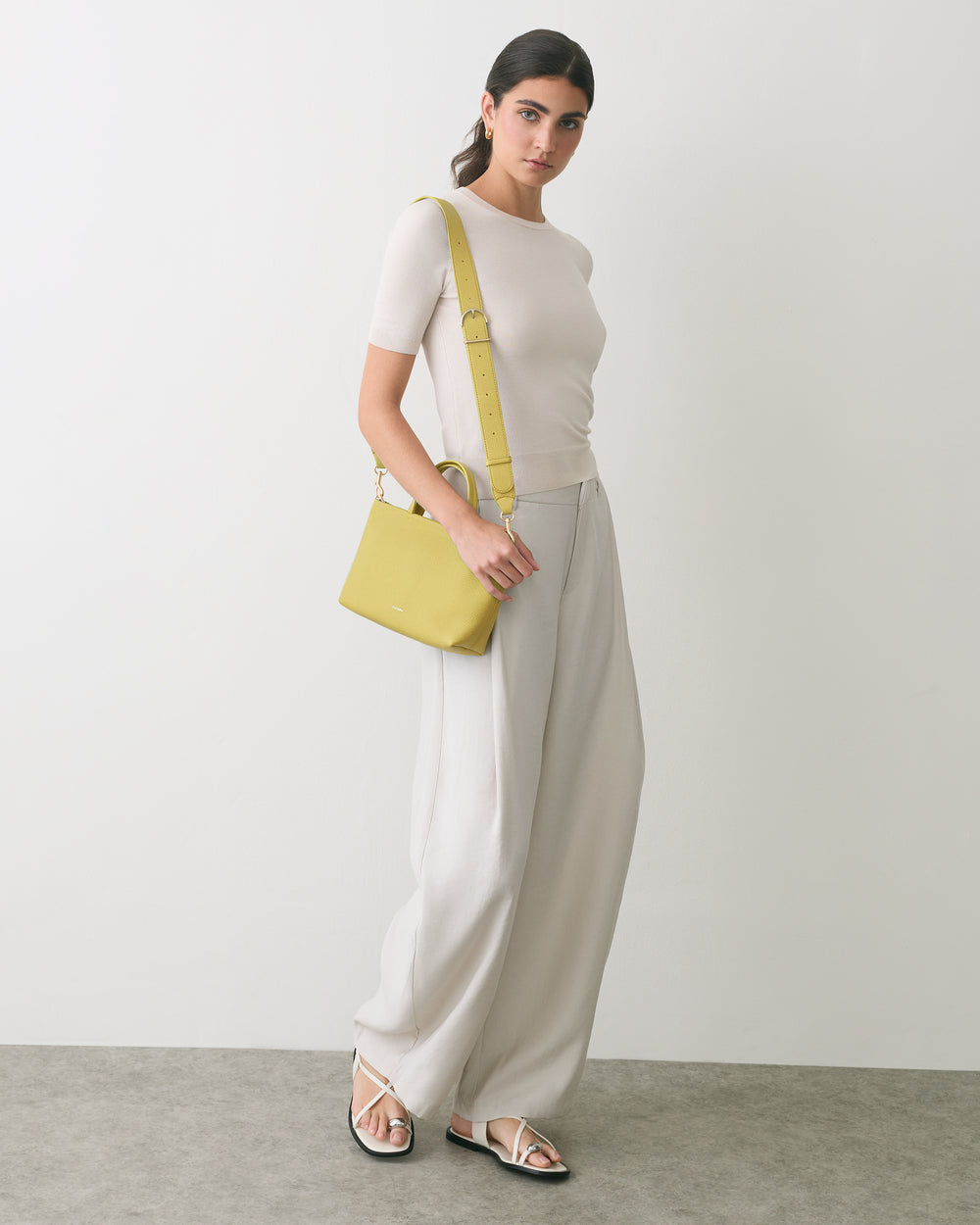 Person in a top and wide pants with a shoulder bag and sandals.