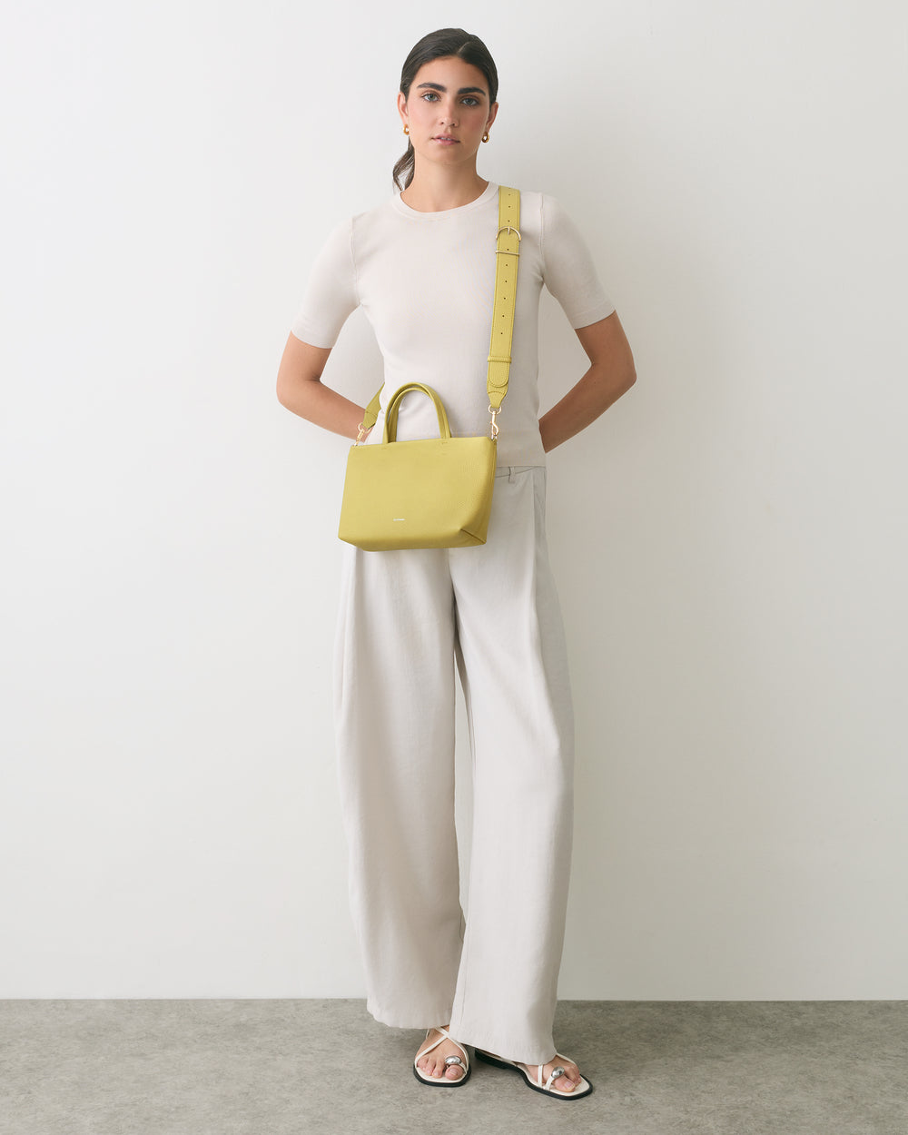 Person in a fitted top and wide-leg pants with a small shoulder bag.