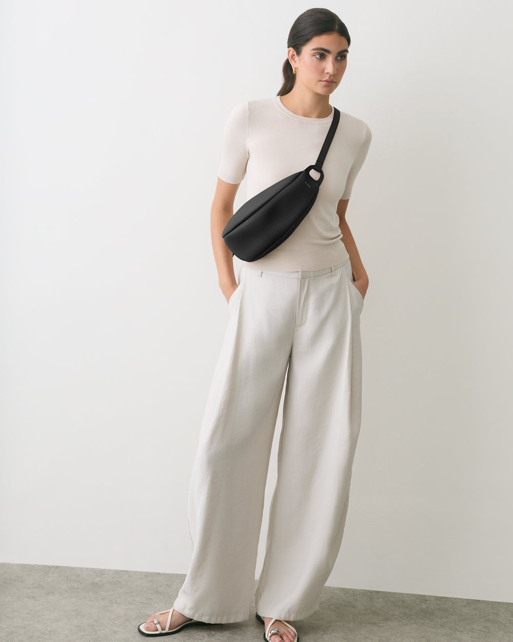 Person standing with hands in pocket wearing a belt bag and wide-leg pants.