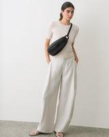 Person standing with hands in pocket wearing a belt bag and wide-leg pants.